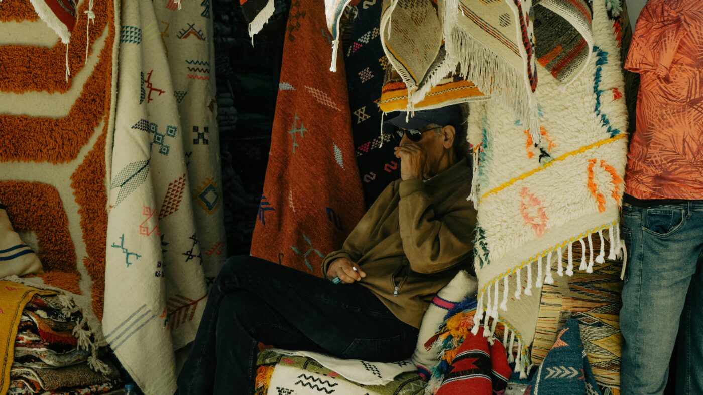 Artisan selling handmade Moroccan rugs in a vibrant souk, showcasing traditional patterns and craftsmanship