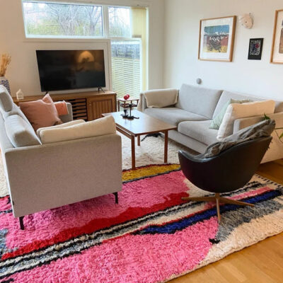 Bohemian rugs in pink tones styled in a modern living room with grey sofas and wooden furniture.