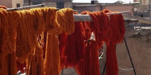 Orange and red dyed wool yarn drying outdoors for Moroccan rug making